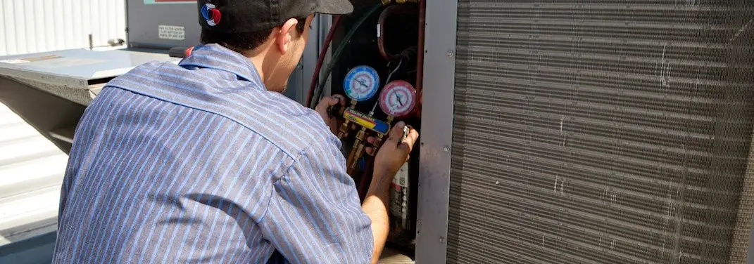 HVAC technician servicing a condenser unit in Rockland